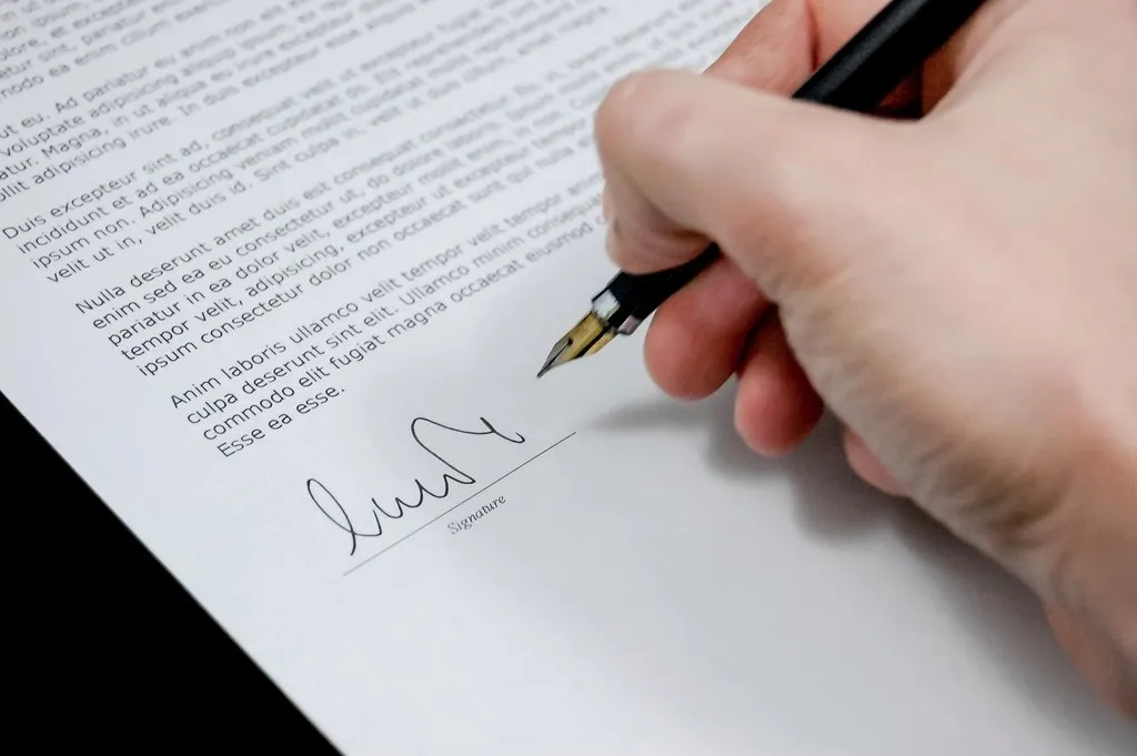 Mano firmando un documento con pluma