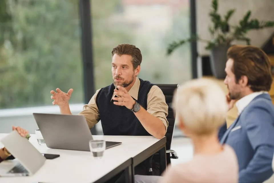 Dos abogados atendiendo a una clienta en una sala de reuniones